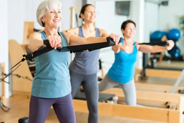 Toning Arms After 60: Empowering Womens Fitness Through Effective Weight Training 2 older woman doing weight training Godalming and resistance in the gym to tone upper arms