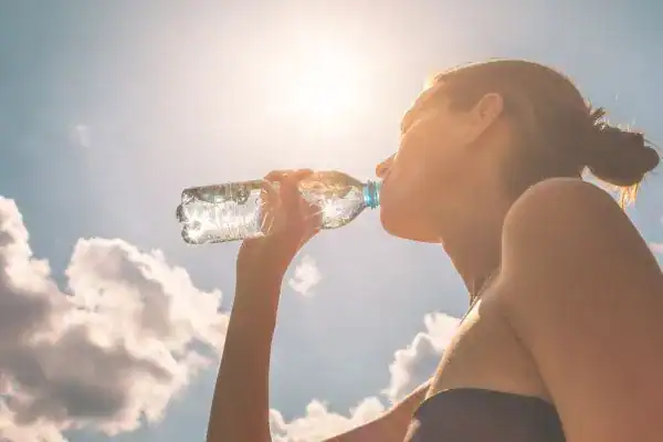 Hydration: The Secret Ingredient for a Toned Stomach and Enhanced Fitness 3 Image of woman drinking water to hydrate Godalming after run.